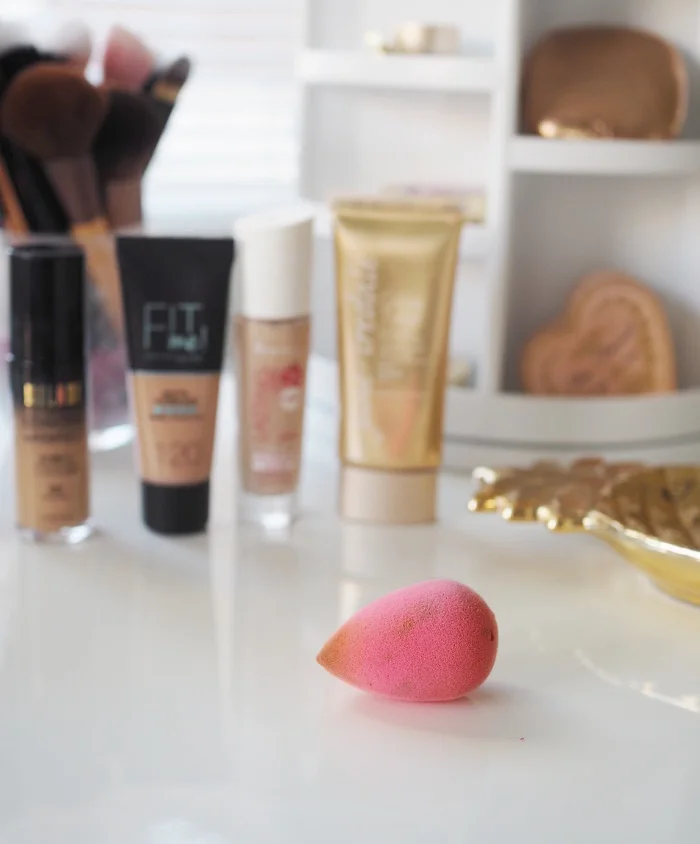 Pinkki beautyblender-meikkisieni meikkivoiteiden edessä