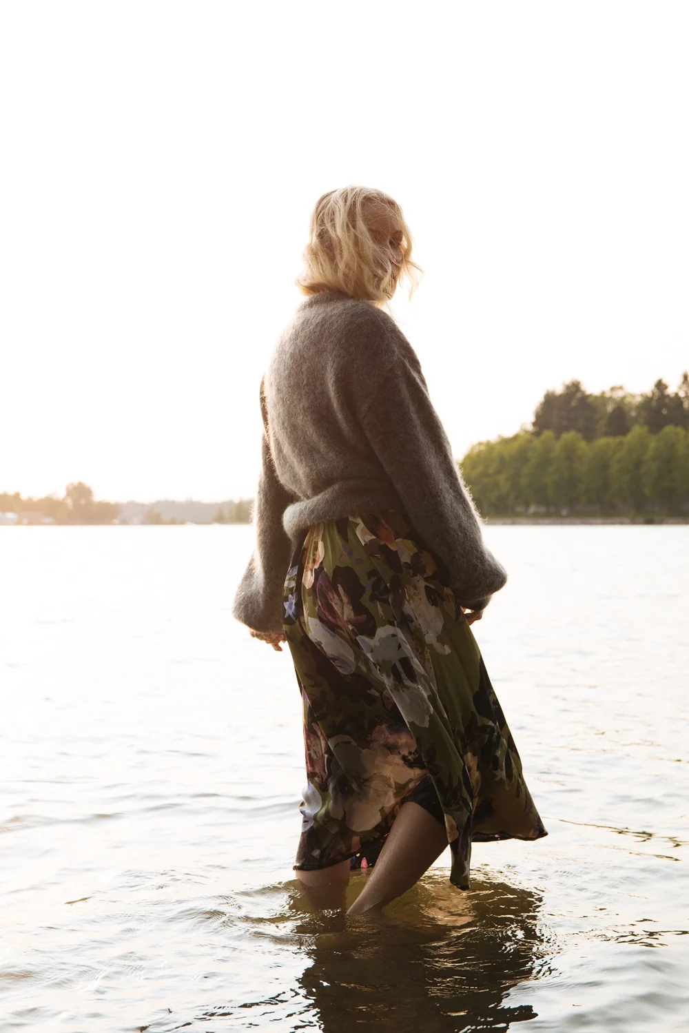 Charlotta seisoo meressä Kaikon Olive Anemone -kuosisessa Wrap Midi Dress -mekossa